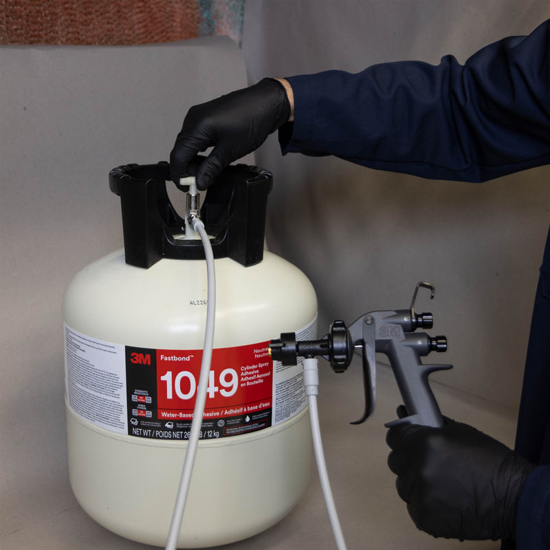Operator connecting 3M Water-Based Spray Gun to Fastbond 1049 adhesive cylinder using hose fitting.