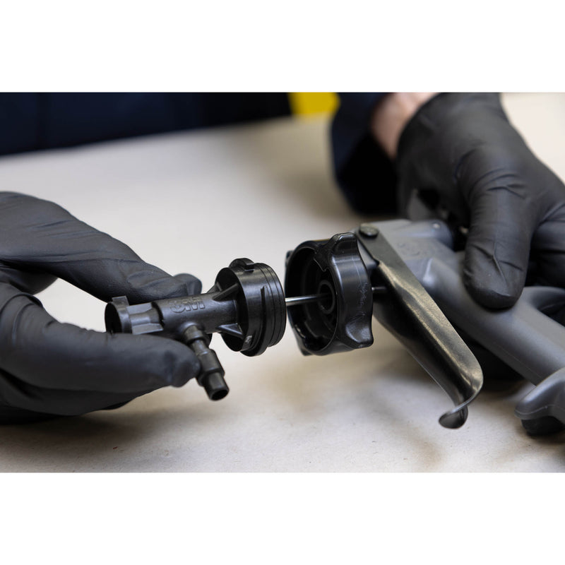 Operator connecting disposable 3M Water-Based Spray Nozzle to applicator system during setup.