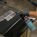 Spraying DAP Weldwood HHR Contact Adhesive onto layered black foam and vinyl for upholstery bonding