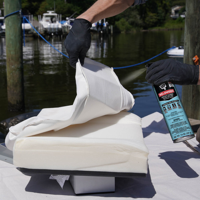 Applying DAP Weldwood HHR Spray Adhesive to foam-backed marine upholstery cushion outdoors near dock