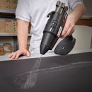 Tec 6300 hot melt spray glue gun dispensing adhesive in a wide pattern across a flat packaging board surface.