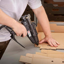 During carton assembly, a Tec 6100 pneumatic glue gun dispenses a bead of hot melt adhesive onto layered cardboard material.