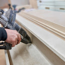 Hot melt adhesive is dispensed along the edge of a wood panel using a pneumatic Power Adhesives Tec 7100 glue gun during assembly work.