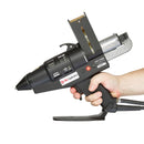 The Power Adhesives Tec 7100-43 glue gun is shown in hand, highlighting the trigger, grip, indicator light, and attached base stand.